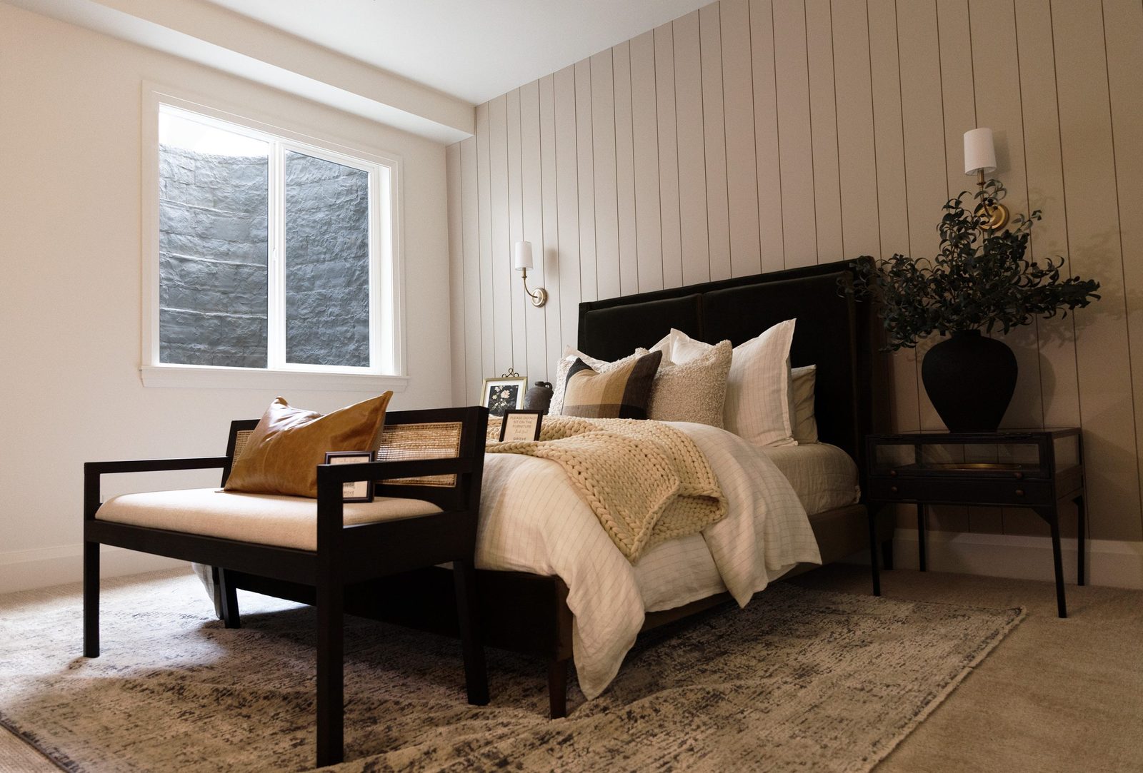 Finished basement bedroom with a large egress window looking into a gray stone-look window well